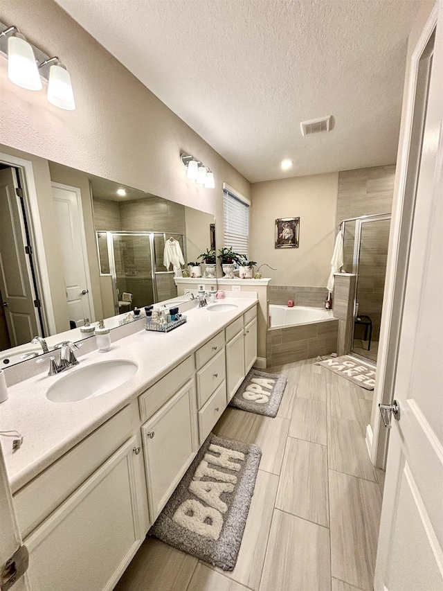 bathroom featuring vanity, plus walk in shower, and a textured ceiling