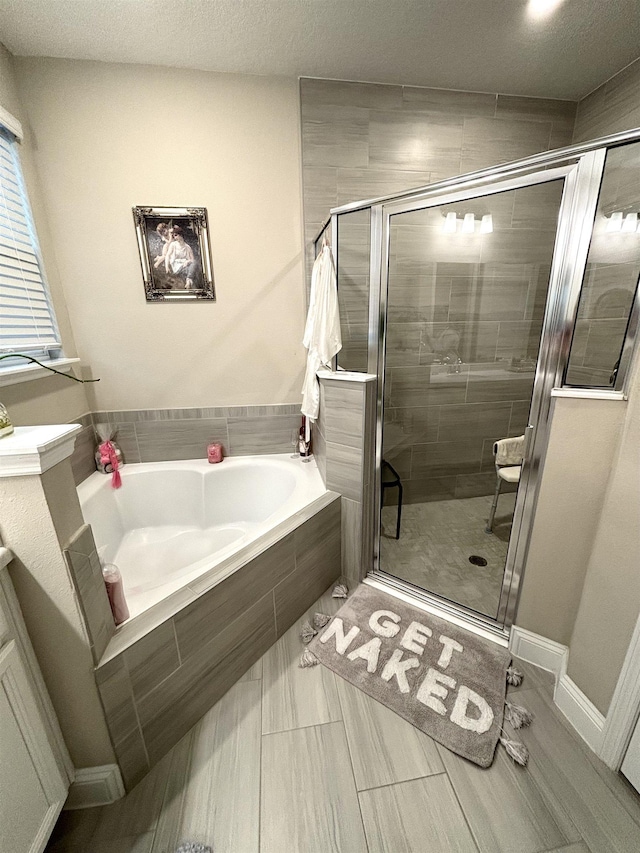 bathroom featuring a textured ceiling and independent shower and bath