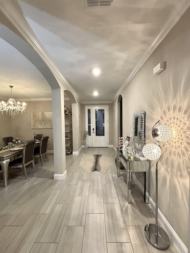 hall featuring hardwood / wood-style floors, an inviting chandelier, and crown molding