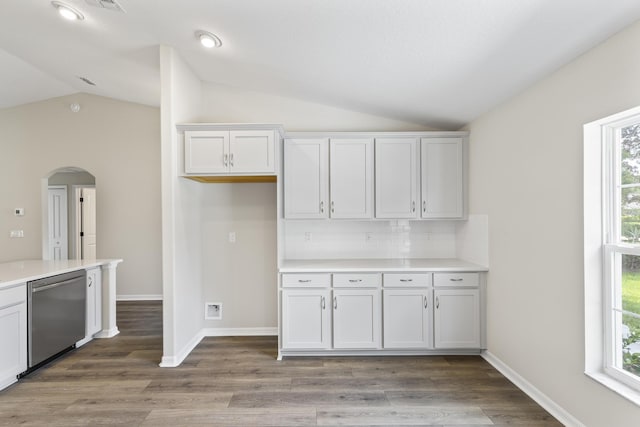 kitchen with white cabinetry, stainless steel dishwasher, vaulted ceiling, and wood-type flooring