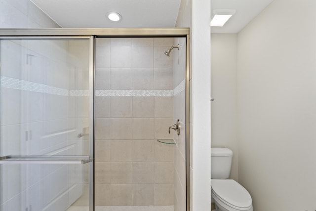 bathroom featuring toilet and a shower with door