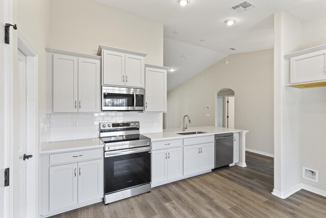 kitchen with decorative backsplash, appliances with stainless steel finishes, sink, wood-type flooring, and white cabinetry