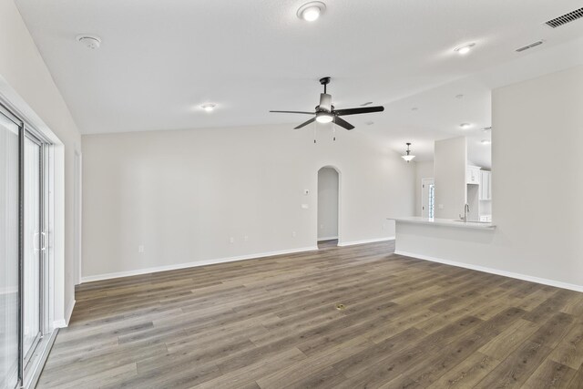 unfurnished living room featuring dark hardwood / wood-style floors, ceiling fan, lofted ceiling, and sink