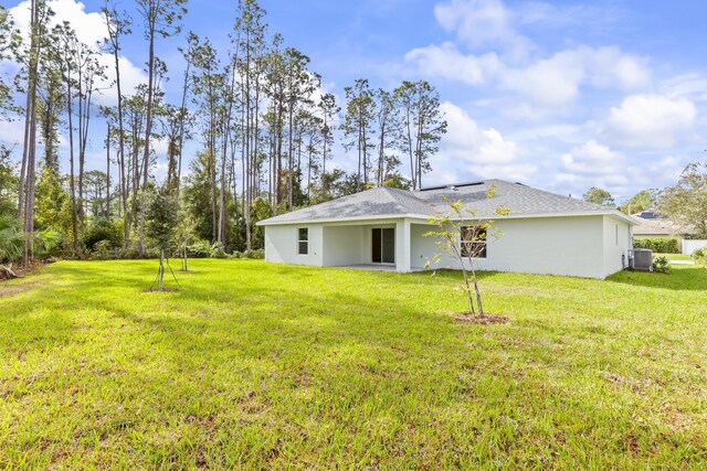 back of property with central AC unit and a lawn