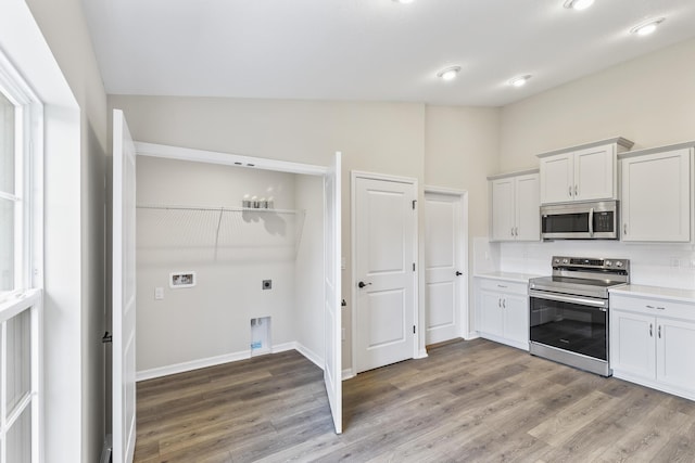 kitchen featuring hardwood / wood-style flooring, white cabinetry, appliances with stainless steel finishes, and vaulted ceiling