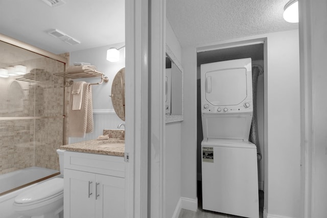 clothes washing area featuring laundry area, visible vents, stacked washer and clothes dryer, a textured ceiling, and a sink