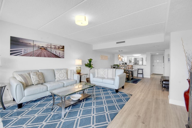 living area featuring visible vents, a textured ceiling, baseboards, and wood finished floors