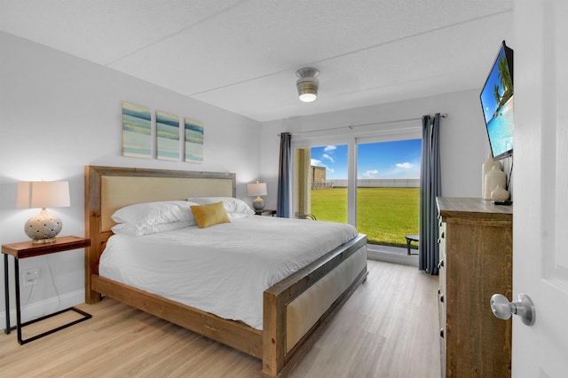 bedroom featuring access to outside, light wood-style flooring, and baseboards