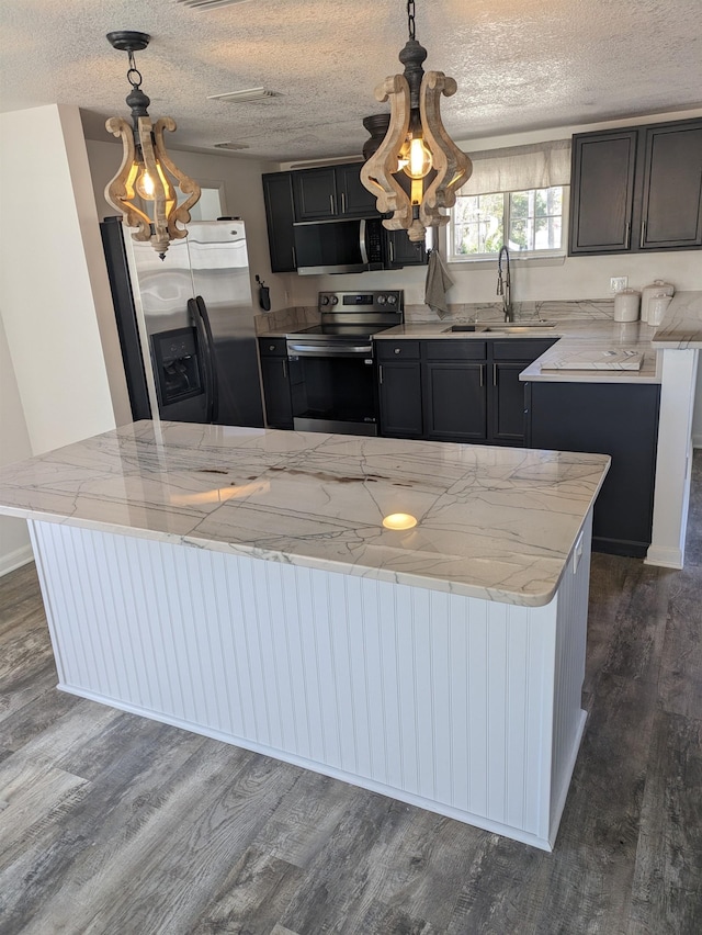 kitchen with appliances with stainless steel finishes, decorative light fixtures, dark hardwood / wood-style flooring, and sink