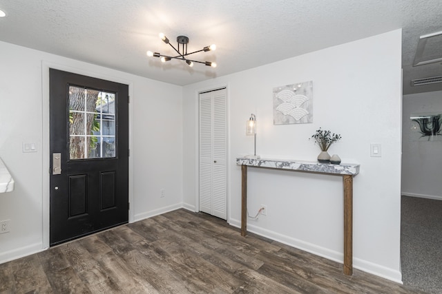 foyer featuring an inviting chandelier, dark hardwood / wood-style floors, and a textured ceiling