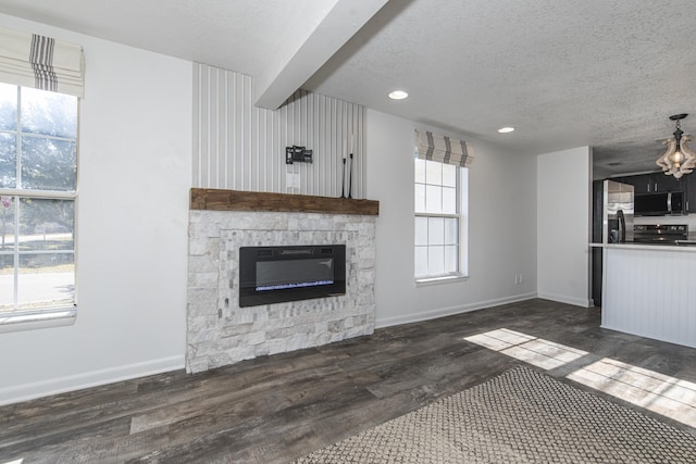 unfurnished living room with plenty of natural light, dark hardwood / wood-style flooring, and a textured ceiling