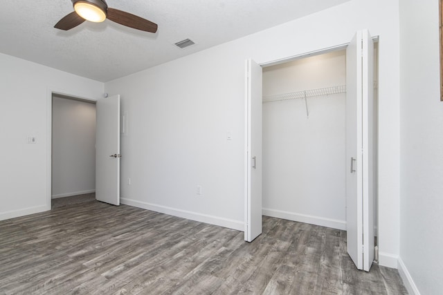 unfurnished bedroom featuring a closet, dark hardwood / wood-style floors, a textured ceiling, and ceiling fan