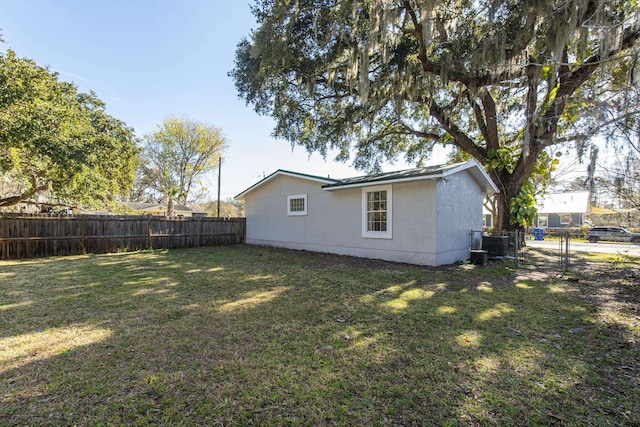 rear view of property with central AC unit and a lawn