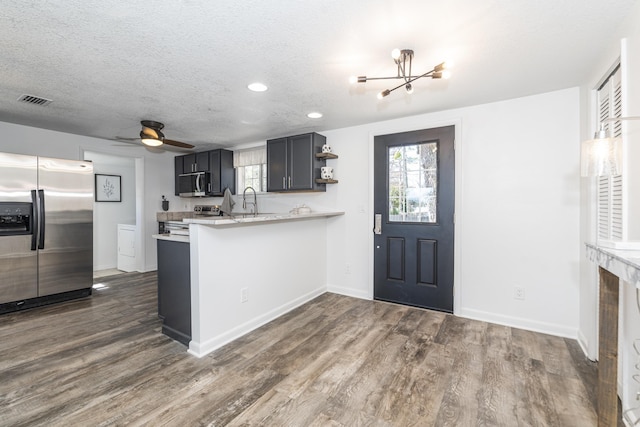 kitchen with dark wood-type flooring, a healthy amount of sunlight, appliances with stainless steel finishes, and kitchen peninsula