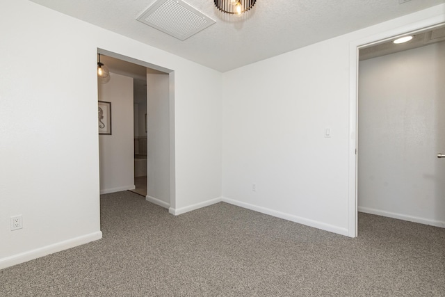 spare room featuring a textured ceiling and carpet