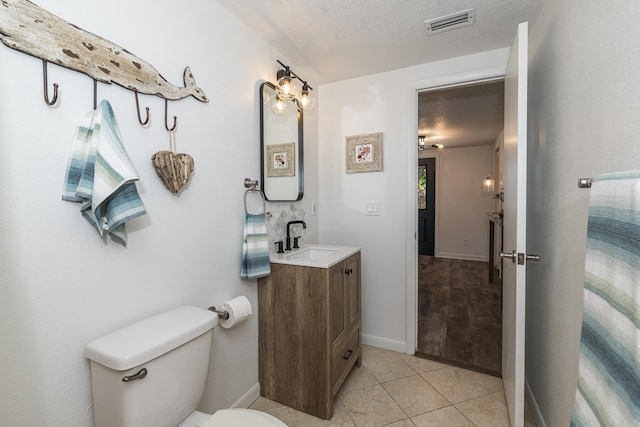 bathroom with vanity, tile patterned floors, toilet, and a textured ceiling