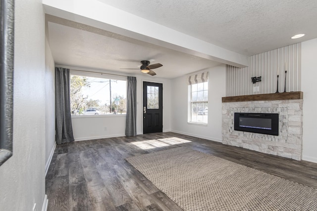 unfurnished living room with ceiling fan, dark hardwood / wood-style floors, a textured ceiling, and a fireplace