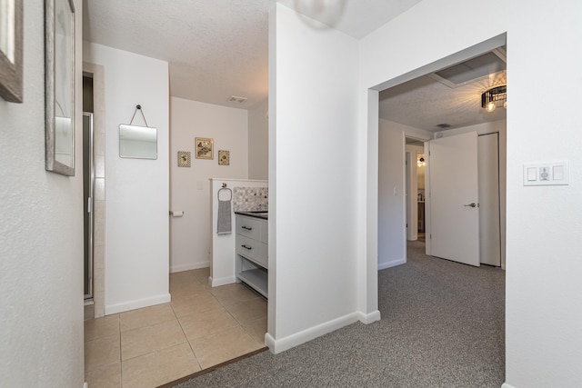 corridor featuring light tile patterned flooring and a textured ceiling