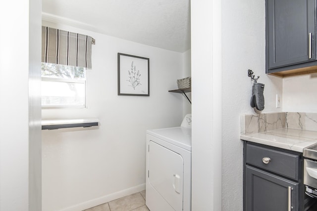 laundry area featuring washer / clothes dryer, light tile patterned floors, and cabinets