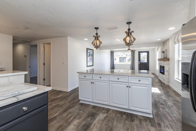 kitchen featuring pendant lighting, white cabinetry, dark hardwood / wood-style floors, a textured ceiling, and stainless steel fridge with ice dispenser