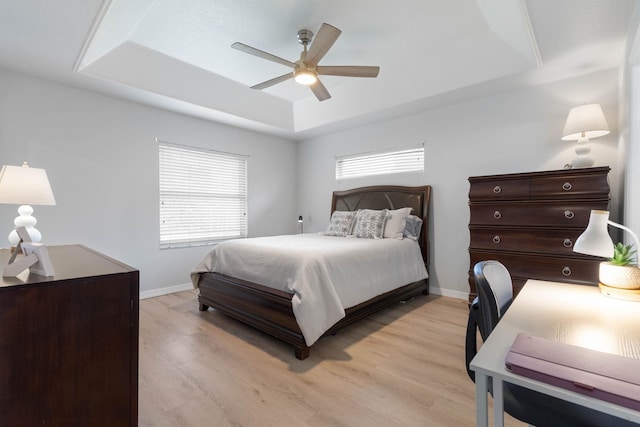 bedroom featuring ceiling fan, a tray ceiling, and light hardwood / wood-style floors