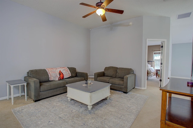 carpeted living room featuring ceiling fan and a textured ceiling