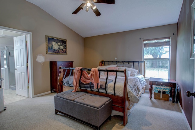 bedroom with ceiling fan, ensuite bathroom, light carpet, and vaulted ceiling