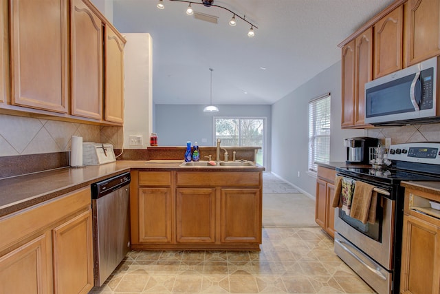 kitchen featuring kitchen peninsula, appliances with stainless steel finishes, backsplash, sink, and decorative light fixtures