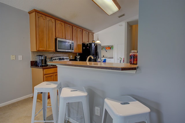 kitchen with light carpet, tasteful backsplash, black refrigerator with ice dispenser, a breakfast bar, and hanging light fixtures