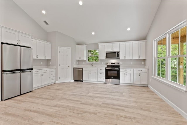 2891 N 8th St, Saint Augustine, FL 32084 - kitchen featuring stainless steel appliances, vaulted ceiling, light countertops, white cabinets, and light wood-style flooring