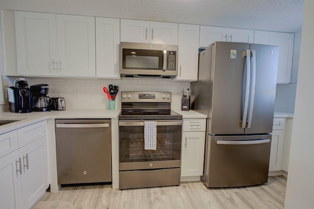 390 A1A Beach Blvd Unit 43, Saint Augustine Beach, FL 32080 - kitchen with appliances with stainless steel finishes, light wood finished floors, white cabinetry, light countertops, and a textured ceiling