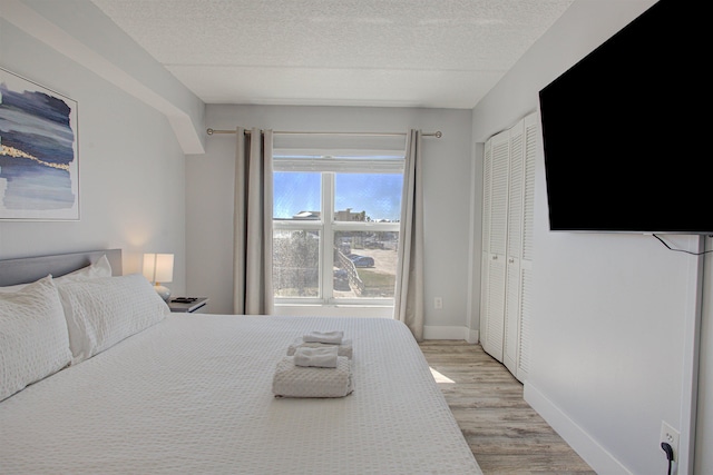 390 A1A Beach Blvd Unit 43, Saint Augustine Beach, FL 32080 - bedroom with light wood finished floors, a textured ceiling, baseboards, and a closet