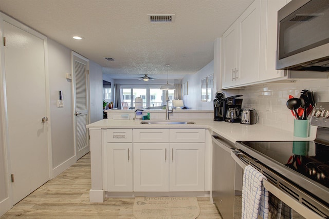 390 A1A Beach Blvd Unit 43, Saint Augustine Beach, FL 32080 - kitchen featuring appliances with stainless steel finishes, a sink, a peninsula, light wood-style floors, and white cabinets