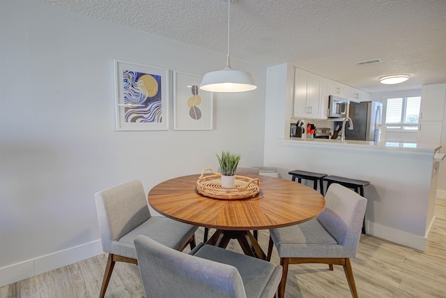 390 A1A Beach Blvd Unit 43, Saint Augustine Beach, FL 32080 - dining room featuring a textured ceiling, light wood-style floors, and baseboards