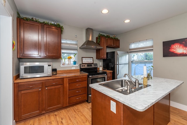 kitchen featuring sink, wall chimney exhaust hood, plenty of natural light, a kitchen island with sink, and appliances with stainless steel finishes