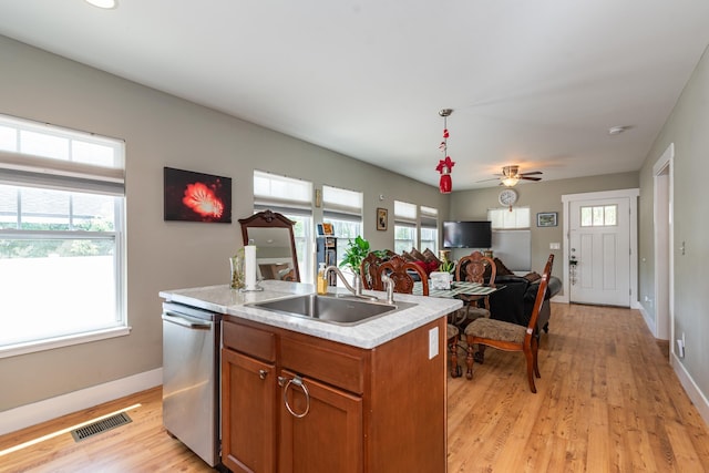 kitchen featuring stainless steel dishwasher, ceiling fan, sink, light hardwood / wood-style floors, and an island with sink