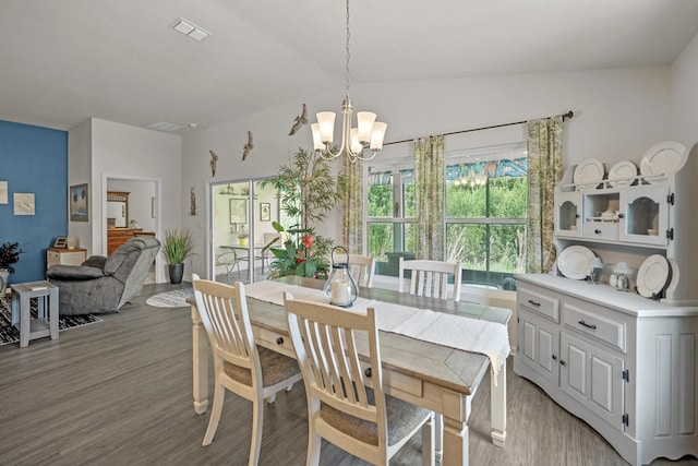 dining area featuring hardwood / wood-style flooring, a chandelier, and vaulted ceiling