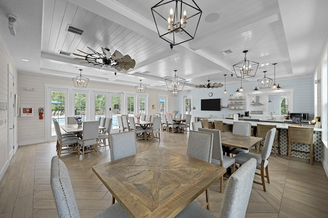 dining room featuring wood ceiling, light parquet flooring, ceiling fan with notable chandelier, a raised ceiling, and beamed ceiling