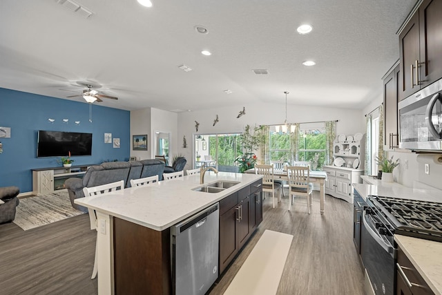 kitchen with appliances with stainless steel finishes, sink, a breakfast bar area, a kitchen island with sink, and dark brown cabinetry