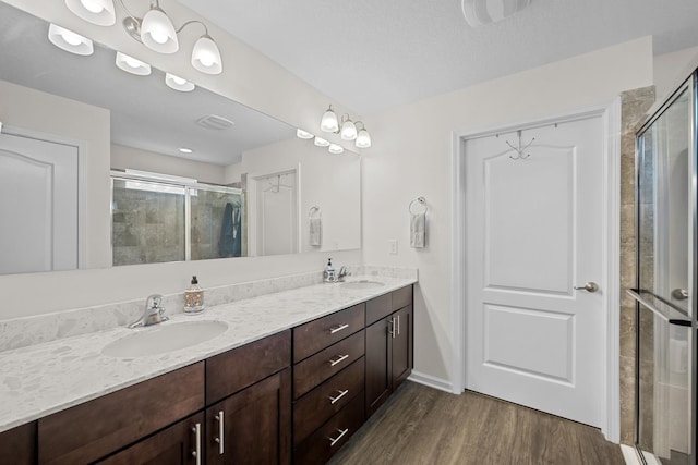 bathroom with wood-type flooring, an enclosed shower, vanity, and a textured ceiling