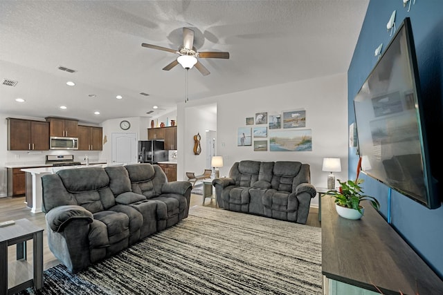 living room featuring a textured ceiling, light hardwood / wood-style flooring, and ceiling fan