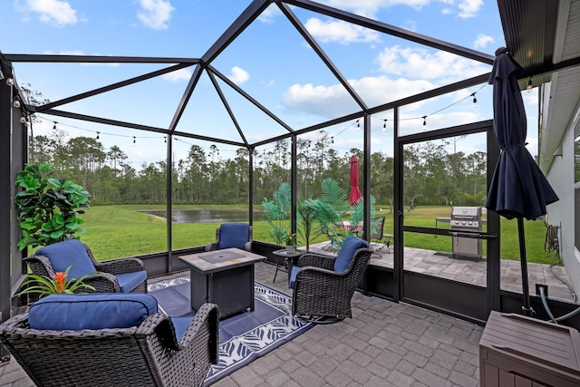 view of patio / terrace featuring grilling area, a water view, an outdoor living space with a fire pit, and glass enclosure