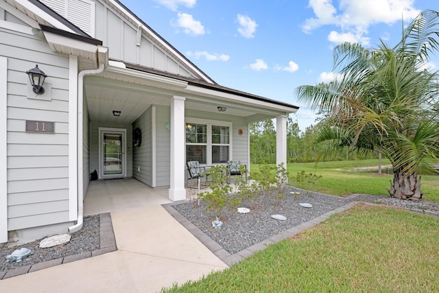 view of exterior entry with a yard and a porch