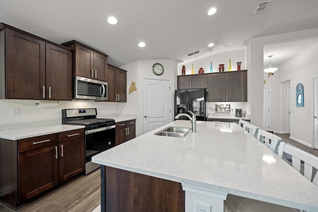 kitchen with stainless steel appliances, an island with sink, and sink