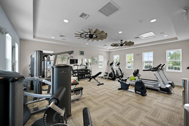 exercise room with a tray ceiling and light colored carpet