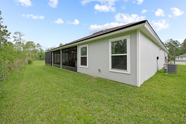 rear view of property with a sunroom, a lawn, and central air condition unit