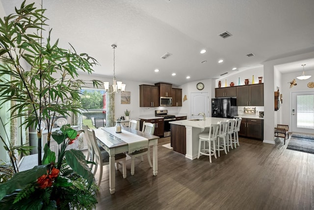 dining room with sink, dark hardwood / wood-style floors, a textured ceiling, vaulted ceiling, and a chandelier