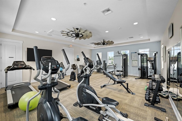 gym with a tray ceiling and carpet floors