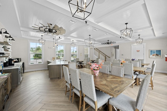 dining room featuring beam ceiling, ceiling fan with notable chandelier, a raised ceiling, and light parquet flooring