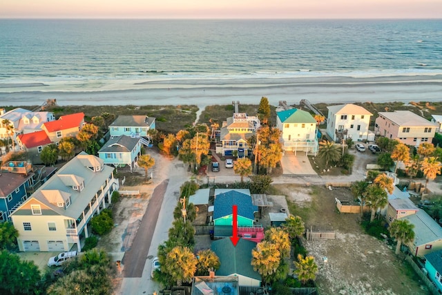 aerial view at dusk with a water view, a residential view, and a view of the beach